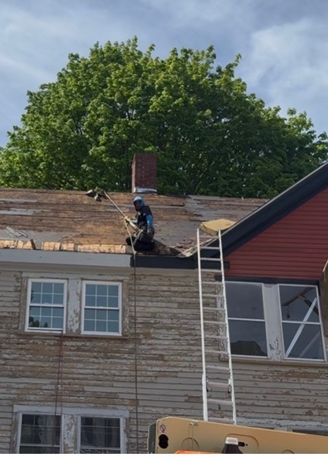 Roof tear-off in progress on a clapboard home